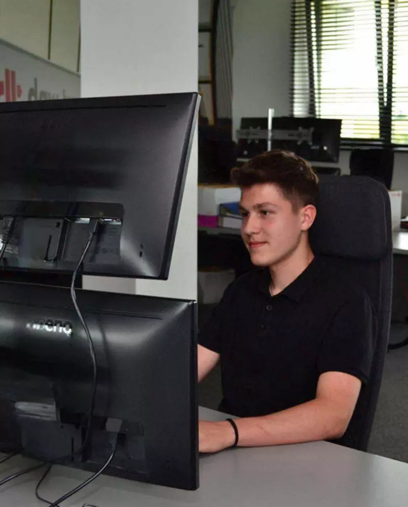 Uczeń patrzy w monitory komputera Uczeń kierunku technik spedytor siedzi przy komputerze i patrzy w monitory