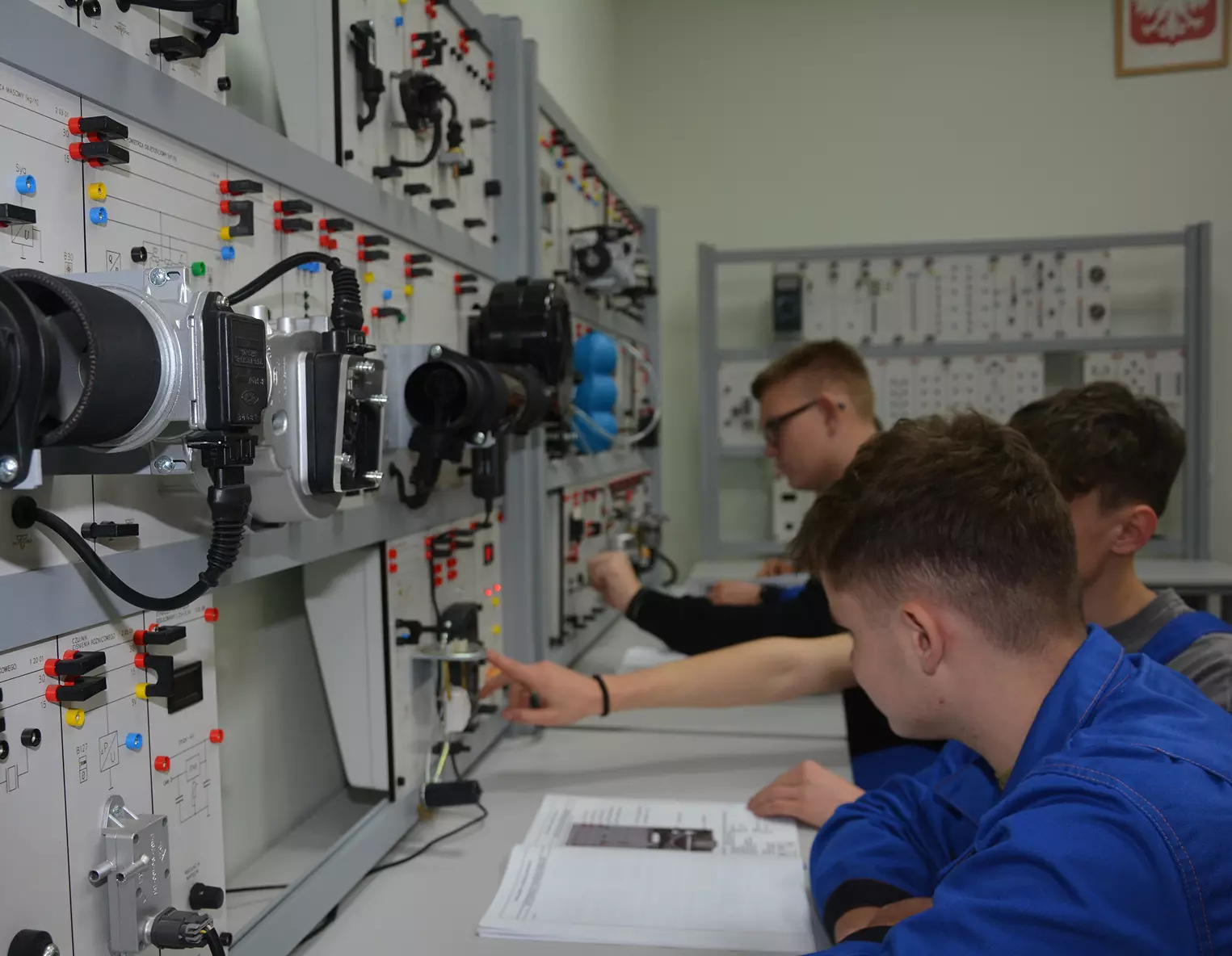 Uczniowie siedzą przed szafą elektryczną Uczniowie kierunku Technik Mechanizacji Rolnictwa i Agrotroniki siedzą przed szafą elektryczną