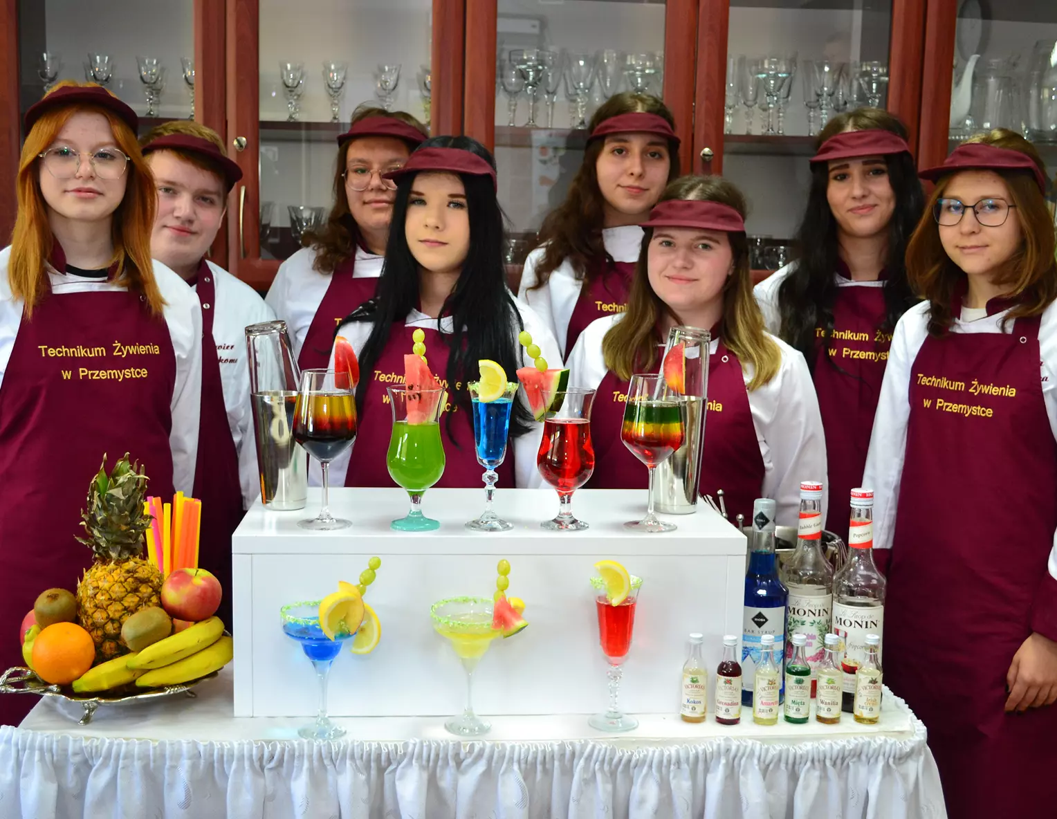 Uczniowie za barkiem, na którym stoją kolorowe napoje Uczniowie kierunku Technik Żywienia i Usług Gastronomicznych za barkiem, na którym stoją kolorowe napoje